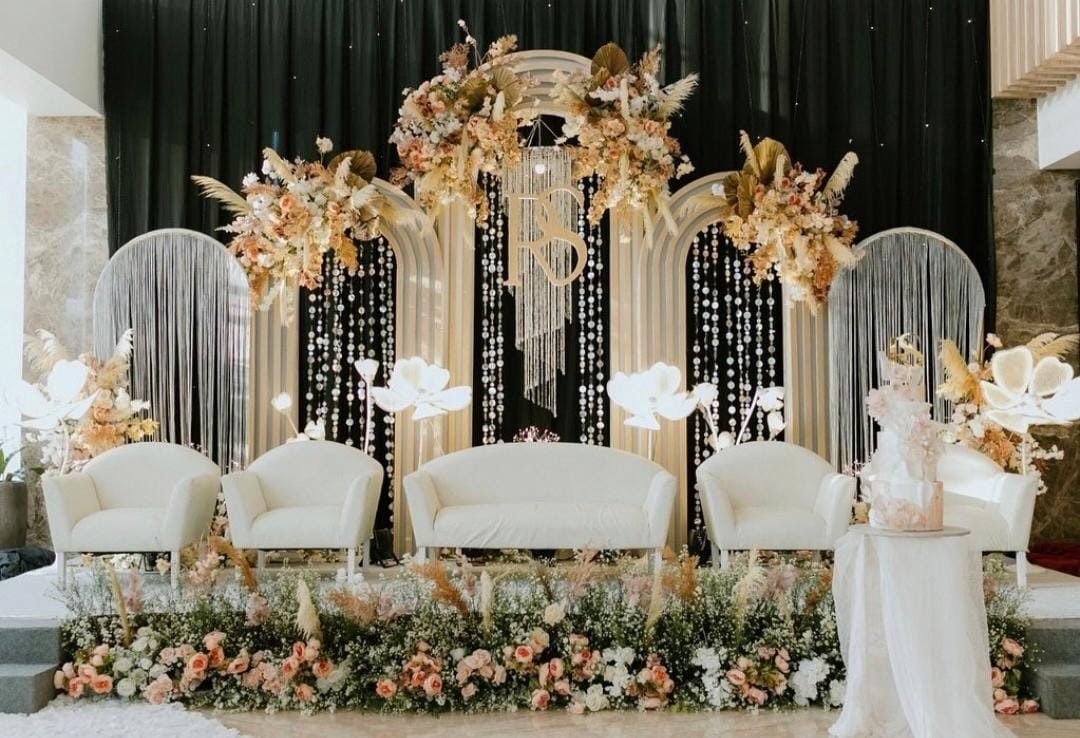 Gold arched backdrop with fringe curtains and dried palm florals