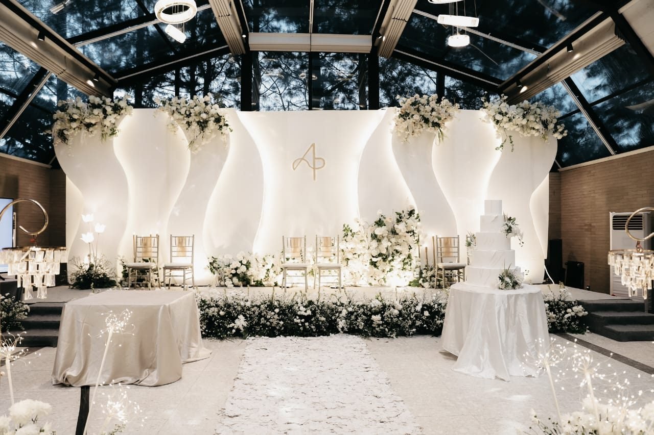 Sculptural white wave-panel backdrop under a glass pavilion ceiling