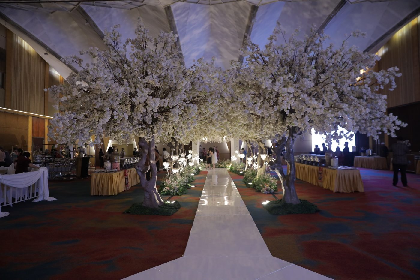 Wide cherry blossom tunnel aisle inside a glasshouse ballroom
